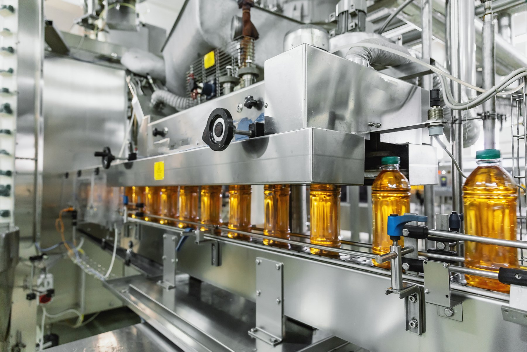 Industrial interior of natural juice plant production. Conveyor belt, filled bottles on beverage factory, industry production line